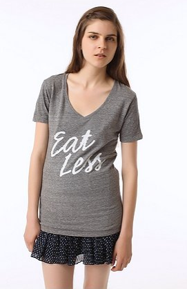 A thin white woman in a gray tshirt that reads Eat Less