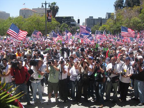 A crowd of protesters holding US flags in Los Angeles CA.