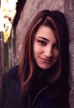 Jennifer, with long brown hair, leaning against a wall