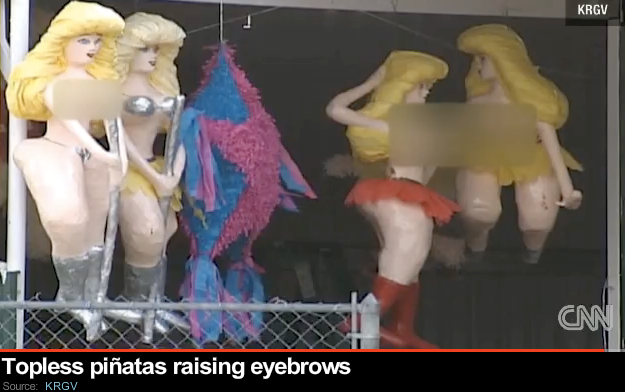 screenshot of video footage, showing the pinatas of blonde women hanging, stripper poles between their legs, breasts fuzzed out by grey strip